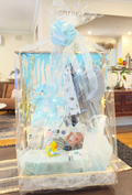 Baby shower gift hamper with baby clothes, plush toys, and assorted baby care items